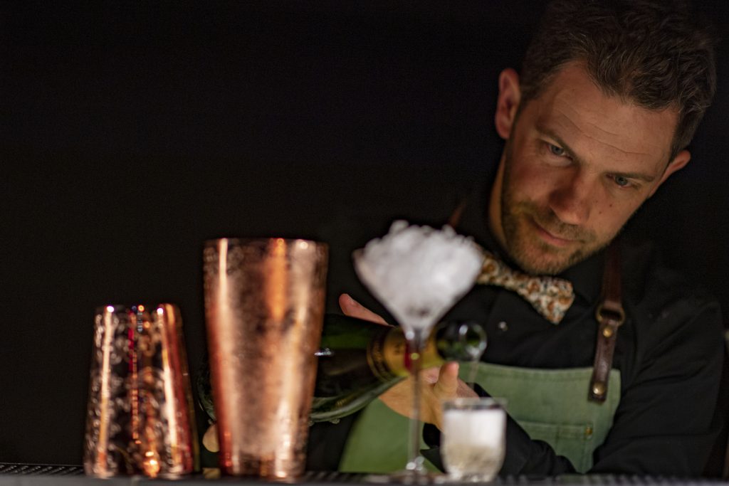 Barman qui fait un cocktail au champagne.